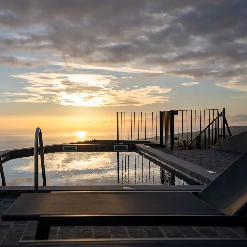 Piscina e espreguiçadeiras ao pôr do sol