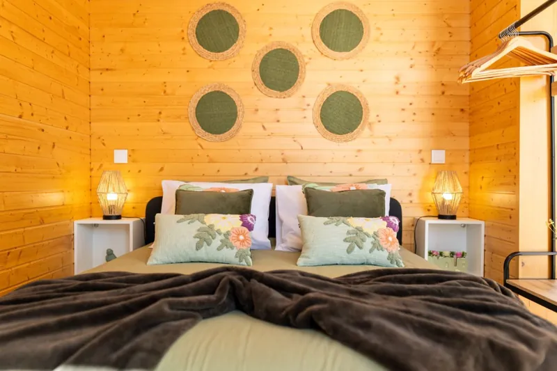 Cama queen com almofadas florais e candeeiros de mesa de cabeceira