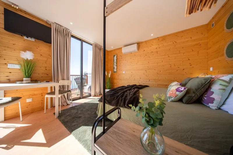 Quarto com mesa, cadeiras e acesso à varanda