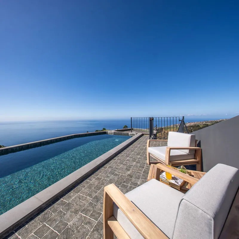 Cadeirões junto à piscina com vista de oceano