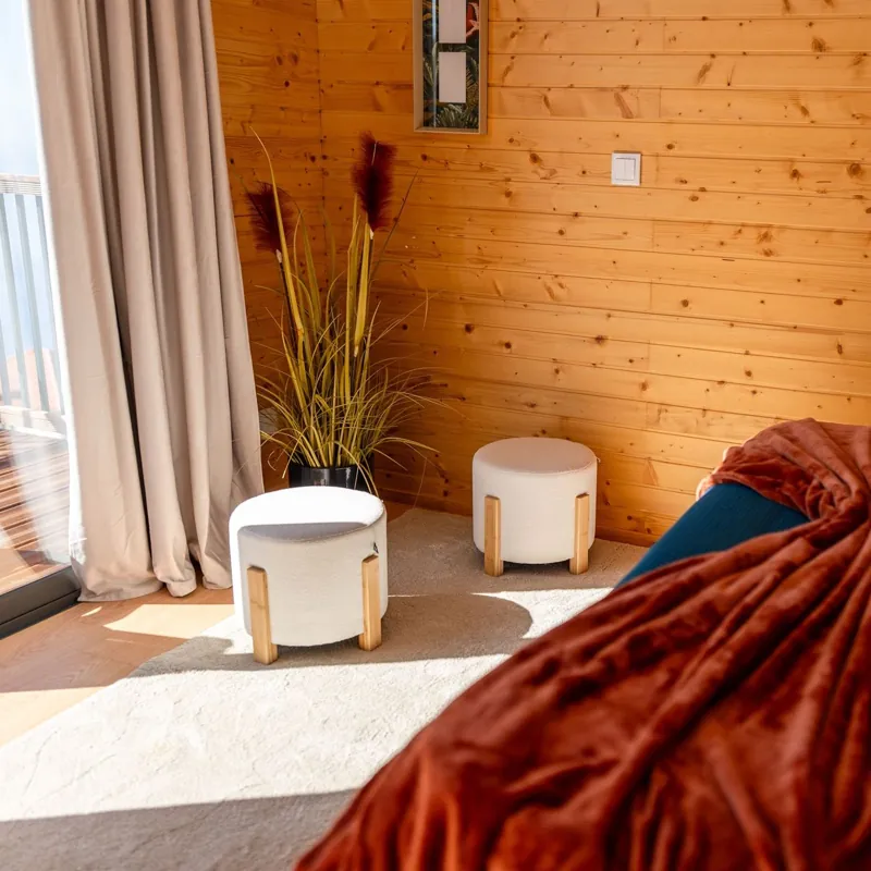 Canto do quarto com pufes, planta e porta para a varanda